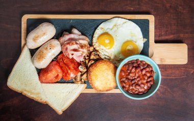 Pastırmalı yumurta, sosis ve domatesler kesme tahtasının üzerinde. Üst görünüm