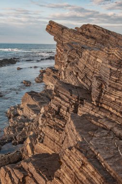 Gökyüzü zeminine karşı kaya ve deniz dalgaları.