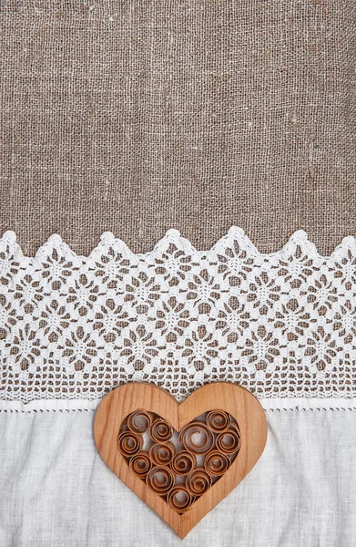 Fondo de arpillera con tela de encaje y corazón de madera — Foto de Stock
