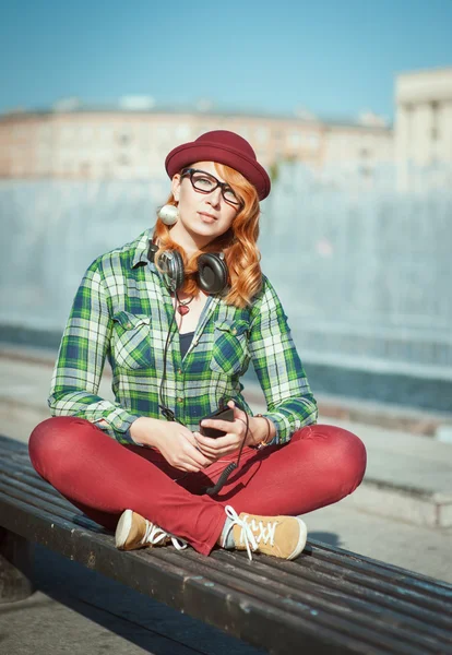 Hipster woman in hat and glasses listening music — Stock Photo, Image
