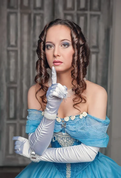 Beautiful medieval woman in blue dress making silence gesture — Stock Photo, Image