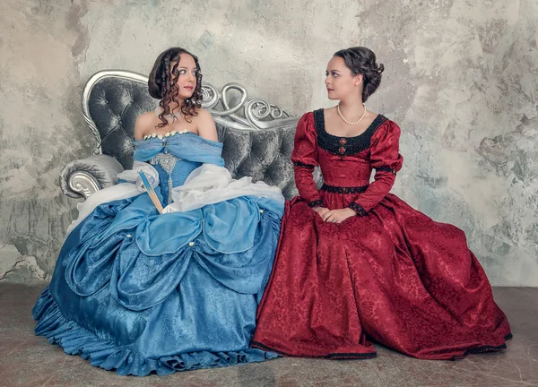 在中世纪的礼服，坐在沙发上的两个漂亮女人 — 图库照片