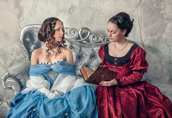 İki güzel kadın kanepede kitap okuma Ortaçağ elbiseler