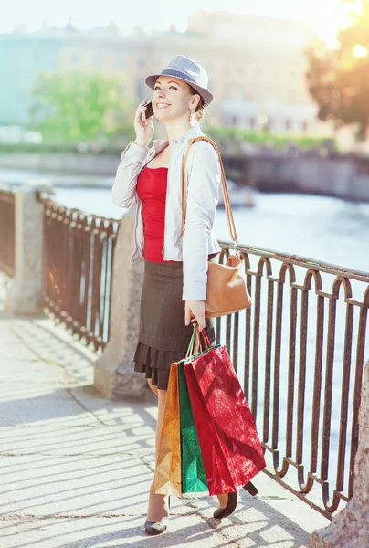 Mooi meisje met boodschappentassen praten op de mobiele telefoon — Stockfoto