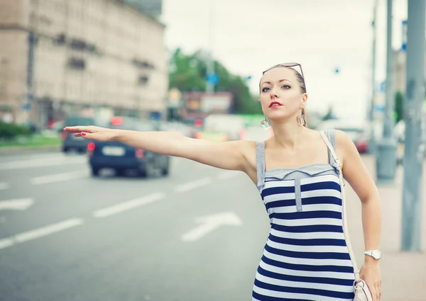 Giovane bella donna che cerca di chiamare un taxi in città — Foto Stock