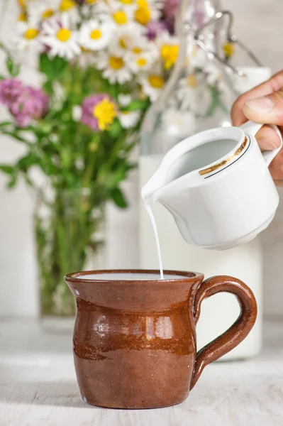 Man hand gieten melk in de mok — Stockfoto