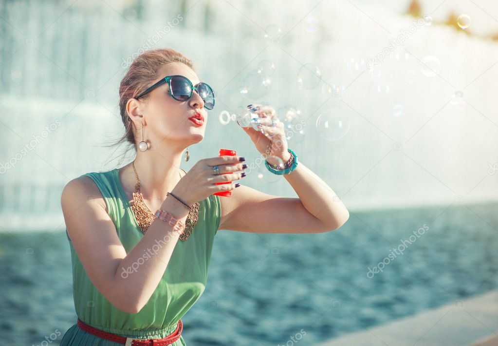 Beautiful girl in vintage clothing blowing bubbles