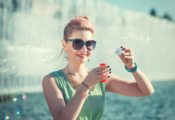 Belle fille en vêtements vintage avec bretelles soufflant des bulles — Photo