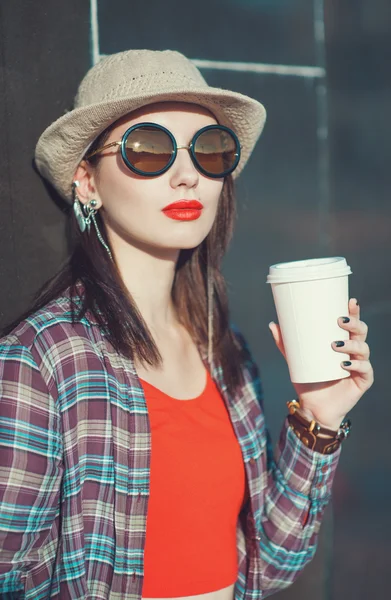 Joven hermosa chica en sombrero y gafas de sol con taza de café — Foto de Stock