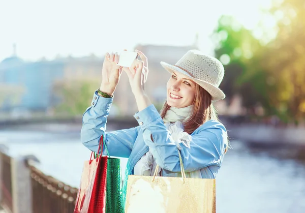 Hermosa chica con bolsas de compras tomadas foto de sí misma —  Fotos de Stock