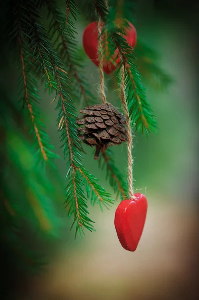 Sfondo natalizio con cono di abete e cuore sul ramo di abete — Foto Stock