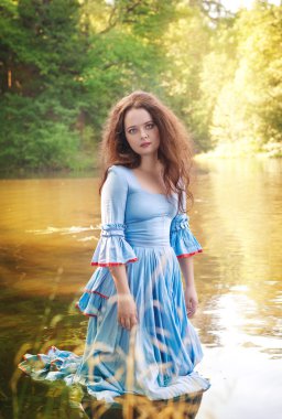 Güzel bir kadınla uzun Ortaçağ elbise ayakta su 