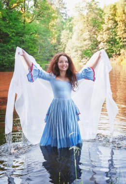 Güzel bir kadınla uzun Ortaçağ elbise ayakta su 