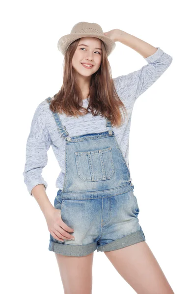 Młody moda dziewczyna w dżinsy kombinezon i kapelusz na białym tle pozowanie — Zdjęcie stockowe