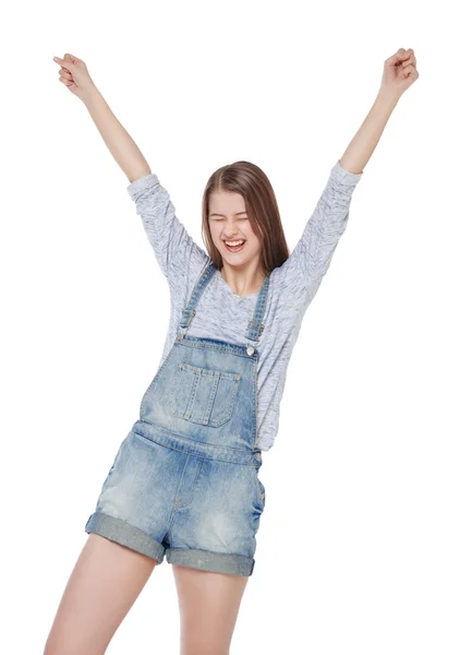 Happy young fashion girl in jeans overalls with hands up isolate — Stock Photo, Image