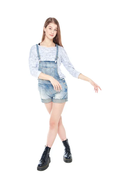Молода дівчина моди в джинсовому комбінезоні позує ізольовано — стокове фото