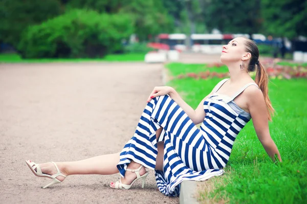 Jeune belle femme à la mode assise sur la pelouse — Photo