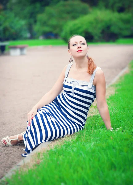 Çimenlikte oturan genç güzel moda kadın — Stok fotoğraf