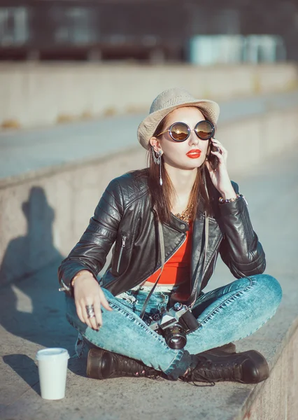 Hipster girl in leather jacket, hat with retro camera and mobile — Stock Photo, Image