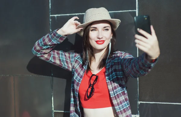 Hermosa joven hipster chica en el sombrero tomando foto de hersel — Foto de Stock