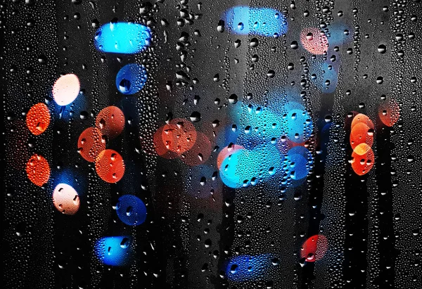 Gocce di pioggia su vetro con luci sfocate. Retroterra astratto — Foto Stock