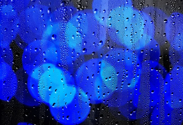 Gotas de chuva em vidro com luzes desfocadas. Fundo abstrato — Fotografia de Stock