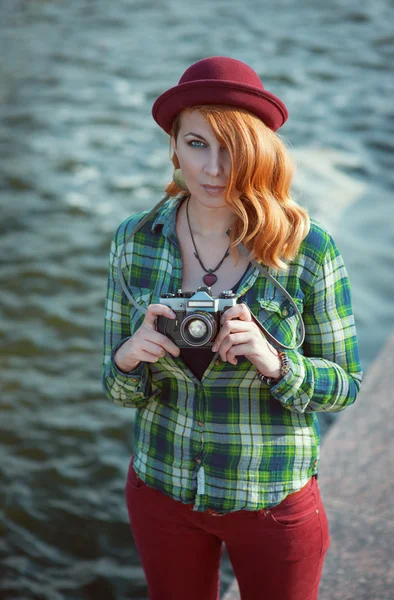 Hipster rödhårig flicka i hatt med retro kamera — Stockfoto