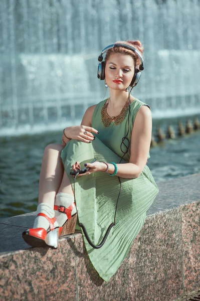 Hipster mode hipster meisje in groene jurk luisteren muziek — Stockfoto