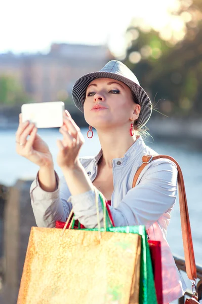 Hermosa chica con bolsas de compras tomadas foto de sí misma en th —  Fotos de Stock