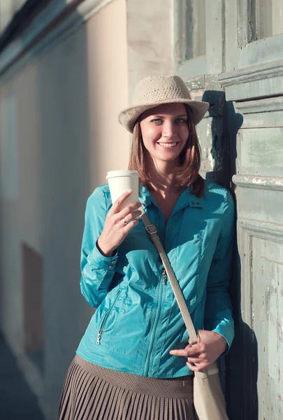 コーヒーのカップと帽子と青いジャケットの美しい流行に敏感な女性 — ストック写真