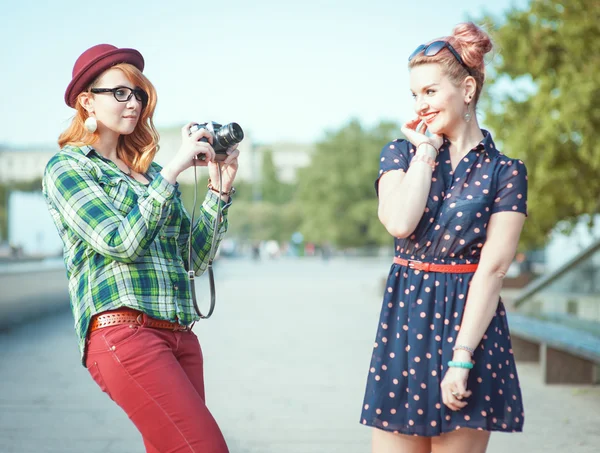 Two beautiful hipster girls taking pictures on film camera outdo — Stock Photo, Image