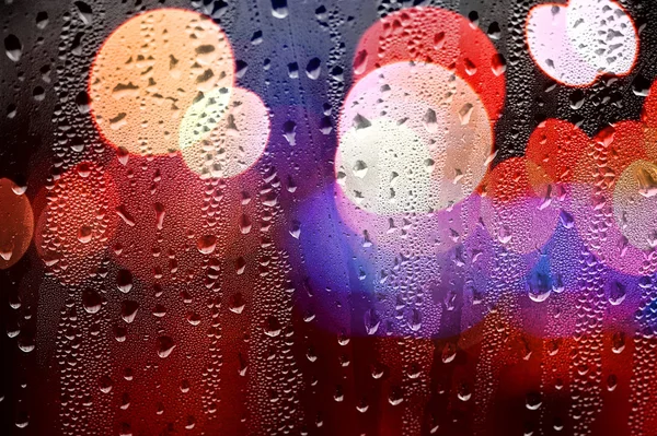 Gocce di pioggia su vetro con luci sfocate. Retroterra astratto — Foto Stock