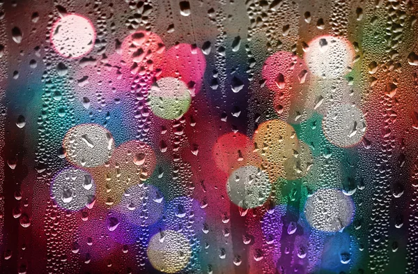 Gotas de lluvia sobre vidrio con luces desenfocadas. Fondo abstracto — Foto de Stock