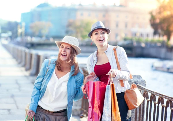 Två glada vackra flickor med shoppingkassar i staden — Stockfoto