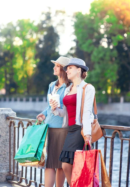 Две красивые девушки с сумками для покупок и чашкой кофе в — стоковое фото