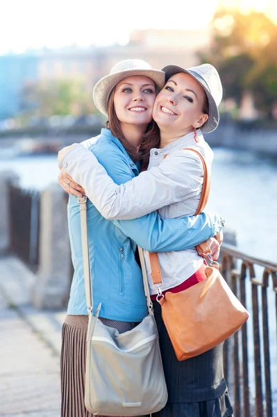 Two beautiful girls laughing and hug in the city — Stock Photo, Image