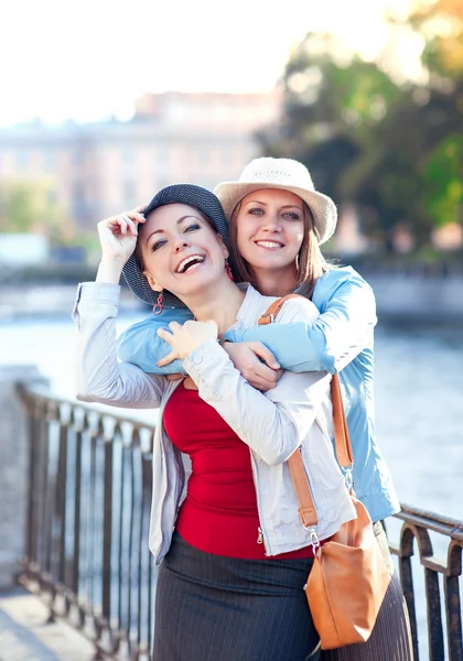 Two beautiful girls laughing and hug in the city — Stock Photo, Image