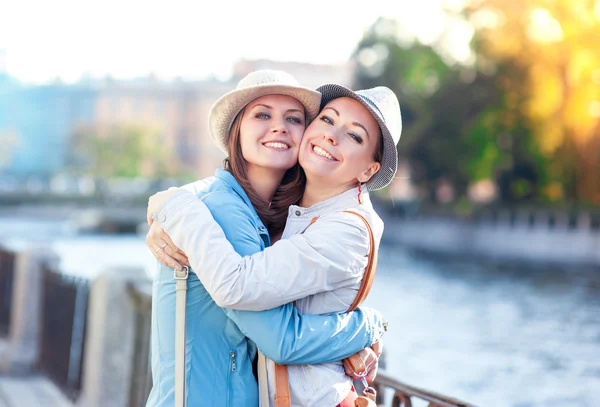 Две красивые девушки смеются и обнимаются в городе — стоковое фото