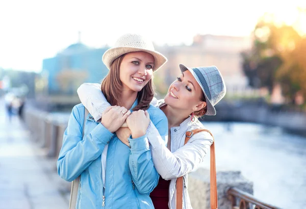 Two beautiful girls laughing and hug in the city — Stock Photo, Image