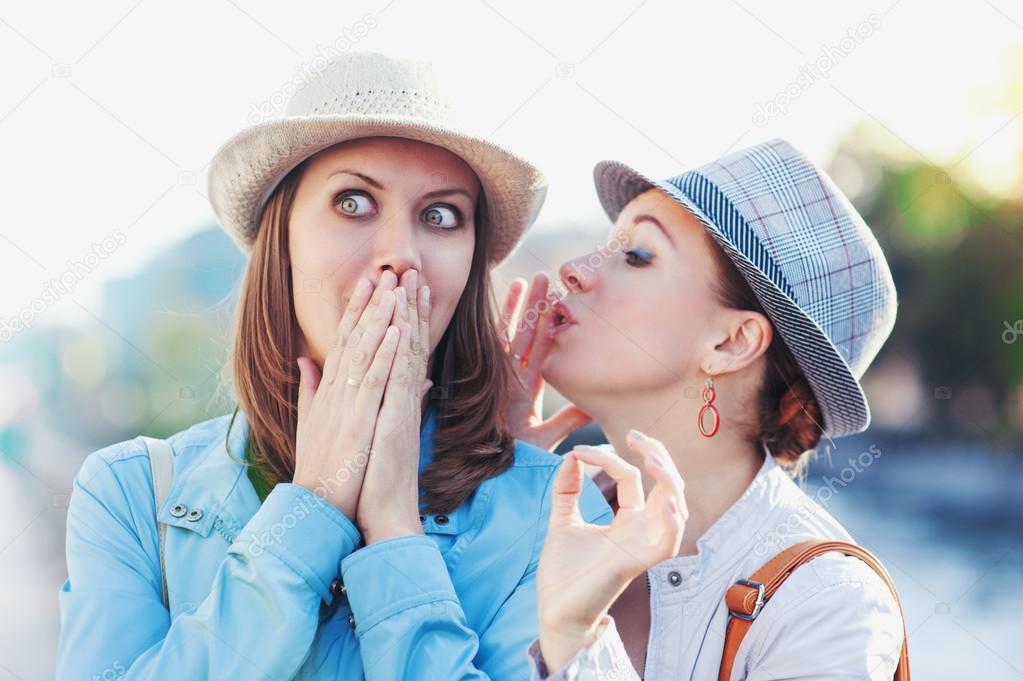 Young beautiful woman telling secret to her friend 