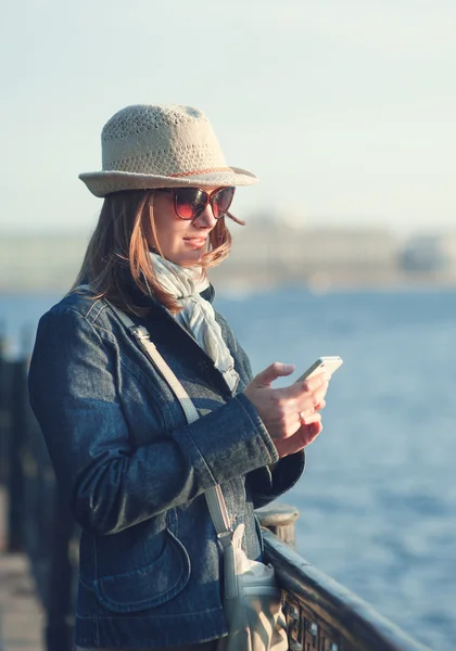 Belle femme en chapeau et écharpe avec téléphone portable dans la ville — Photo