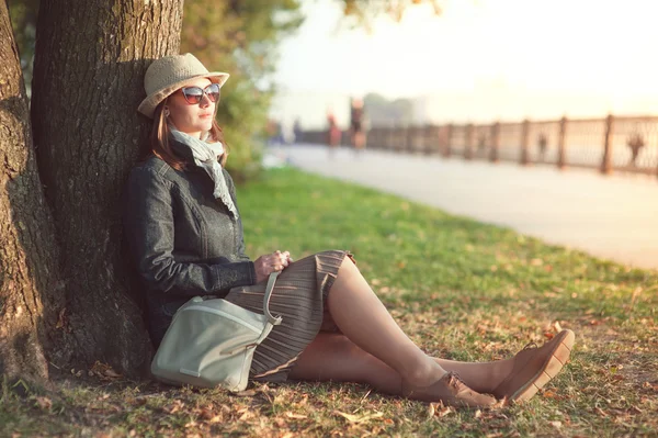 Hermosa mujer en sombrero y bufanda disfrutar de la luz del sol en la ciudad — Foto de Stock