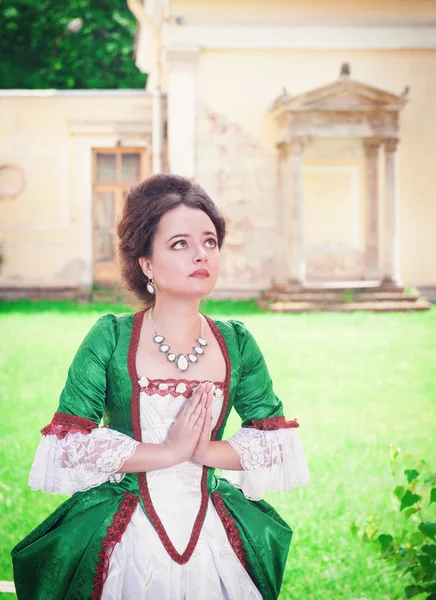 Prachtige middeleeuwse jongedame in groene jurk bidden — Stockfoto
