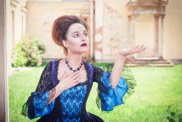 Mooie vrouw in blauwe middeleeuwse jurk uitrekken hand aan someth — Stockfoto