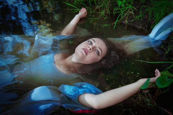 Joven hermosa mujer ahogada en vestido azul acostado en el agua — Foto de Stock