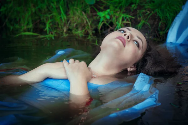 Молодая красивая утонувшая женщина в синем платье лежит в воде — стоковое фото