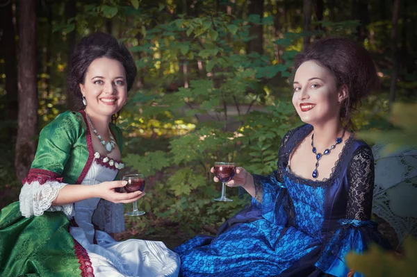 Två unga vackra kvinnor i medeltida klänningar ha picknick — Stockfoto