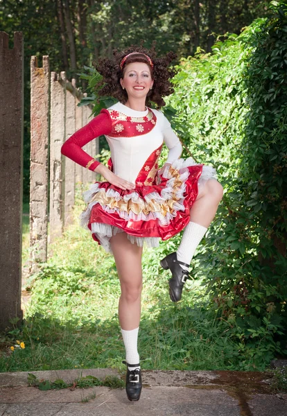 Ung kvinna i irländsk dans klänning och peruk dans — Stockfoto