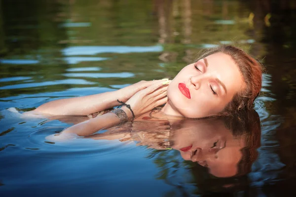Schöne junge Frau im Wasser liegend — Stockfoto