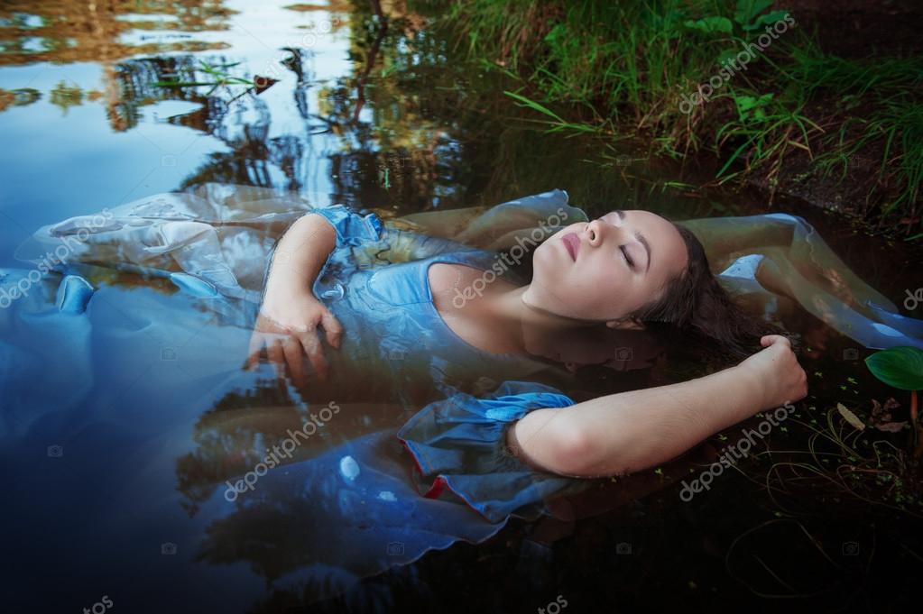 Young beautiful drowned woman lying in the water Stock Photo by